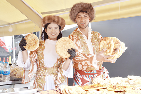 10月2日,身著民族特色服飾的海如尼達·買買提夏(右)和表妹凱比努爾·艾力麥麥提(左)在攤位。(董易鑫 攝)