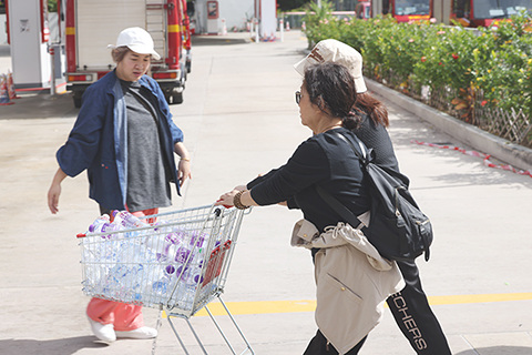 ◎ 十一月二十七日,香港大埔宏福苑五級大火後,社區力量迅速集結。志願者們推著堆滿礦泉水的購物車穿梭現場,泡沫箱上「長沙灣」字樣見證跨區援助。映照著香港市民火場外築起的溫情補給線。圖為一群志願者正在運輸三箱盒飯到臨時救助站。(香港中通社記者 鄧梓杰 攝)