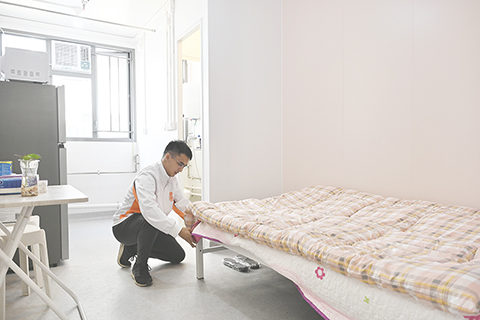 ◎ 十二月十二日,過渡性房屋項目「七星薈」項目主任龐學旻在位於香港元朗的「七星薈」過渡性房屋內整理設施。(中新社記者李志華 攝)