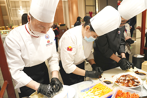 哈薩克斯坦阿斯塔納,拉扎特(左二)正配合中國師傅製作烤鴨卷。(中新社記者 單璐 攝)