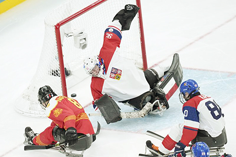 ◎ 三月十五日,中國隊球員汪之棟(左)射門得分。冬殘奧會殘奧冰球銅牌賽中,中國隊三比二戰勝捷克隊,奪得季軍。(新華社記者李京 攝)