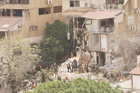 ◎ 以色列軍方四月六日發表聲明確認,在五日伊朗發動的導彈襲擊中,以色列北部城市海法一棟居民樓部份坍塌,造成四人死亡,目前四具遺體已被找到。圖為六日,在以色列北部城市海法,應急反應人員在遭襲現場工作。(新華社發 吉爾.科恩.馬根 攝)