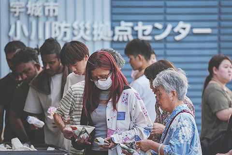◎ 圖為七月二十九日,民眾在日本熊本縣宇城市一處避難所外領取食物。(新華社記者 賈浩成 攝)